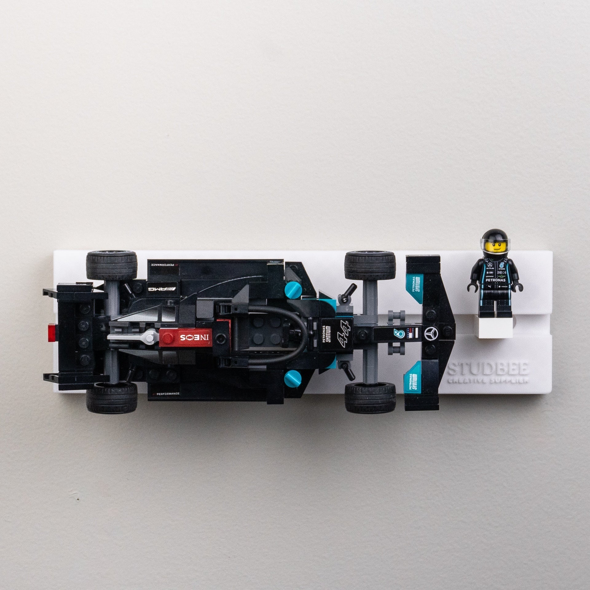 A single-tier white shelf with a detailed black racing car model and a mini-figure in racing attire beside it.